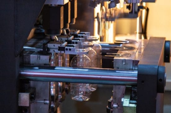Three plastic bottles in a factory machine